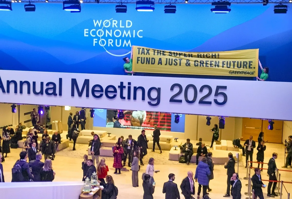 Volunteers hold a banner, put up by rights group Greenpeace, at the main venue of the World Economic Forum (WEF) Annual Meeting 2025, in Davos, Switzerland (PTI Photo)